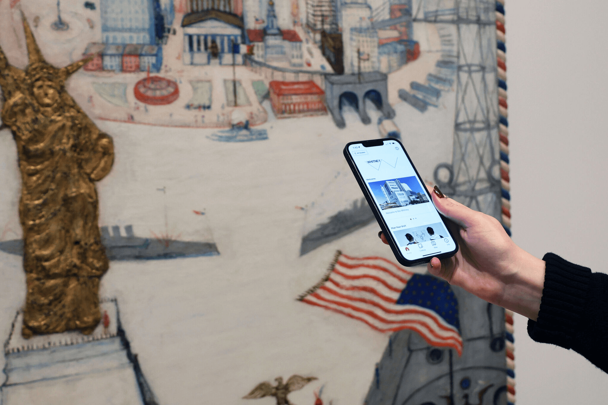 Visitor holding up a phone in front of artwork